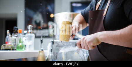 Barkeeper bricht Eis mit Holzhammer Stockfoto