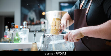 Barkeeper bricht Eis mit Holzhammer Stockfoto