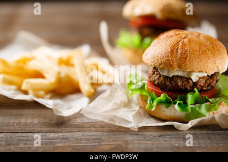 Hausgemachte leckere Burger und Pommes Frites auf Holztisch Stockfoto