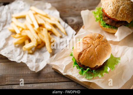 Hausgemachte leckere Burger und Pommes Frites auf Holztisch Stockfoto
