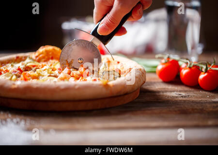 Frischen Pizza aufschneiden mit Walze Messer. Stockfoto