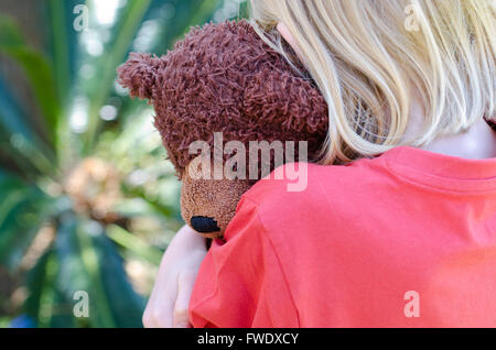 Kleines Mädchen umarmt den braunen Teddy schließen Stockfoto