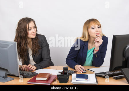 Büroangestellte, die der Kollege sitzt neben starrte auf einem Computermonitor mit Abneigung betrachten Stockfoto