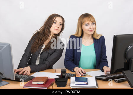 Büroangestellter schaut auf dem schlauen sitzt neben einem Computer Monitor-Kollege Stockfoto