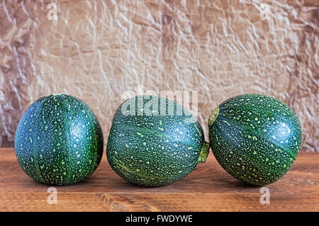 Drei acht-Ball-Kürbisse auf einem Holztisch mit braunen faltige Pergament Papierhintergrund. Stockfoto