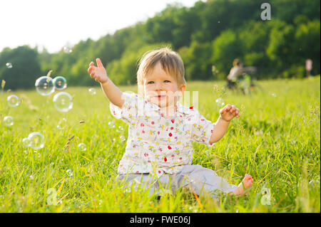 Kind fängt ein Seifenblasen. Stockfoto