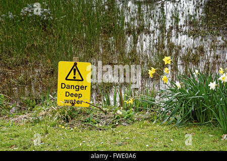 Gelbes Warndreieck am Wasserrand. Stockfoto