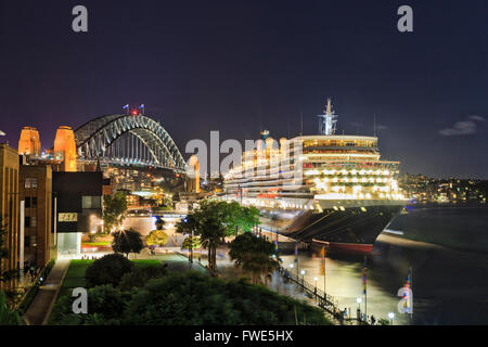 Sydney Harbour Bridge, Wolkenkratzer und Übersee Passagierterminal mit angedockten Schiff vom Circular Quay bei Sonnenuntergang. Stockfoto