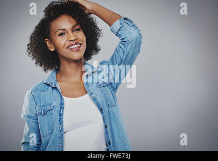 Glücklich temperamentvolle junge afroamerikanische Frau mit lockigem Haar stehend mit der Hand an den Kopf, schaut in die Kamera mit einem lov Stockfoto