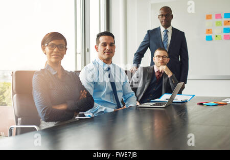 Vier zuversichtlich Erfolgreiche multirassischen diverse Geschäftspartner oder Mitarbeiter an einem Konferenztisch in einem Meeting sitzen und p Stockfoto