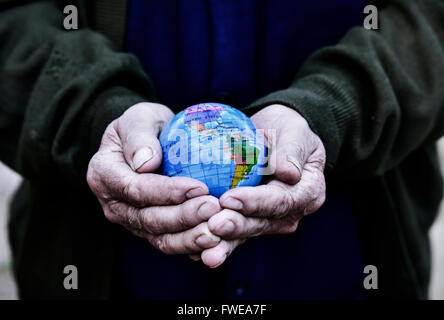 Nahaufnahme von einem alten kaukasischen Mann mit einer Weltkugel in seinen Händen, mit einem dramatischen Effekt Stockfoto