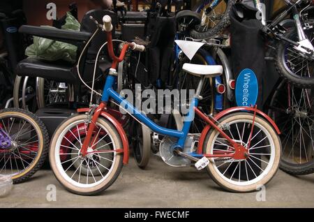 Viel Hoole, Preston, Lancashire. Ein restauriertes handgemaltes Kindes Fahrrad in blau und rot, sitzt im Lager auf der International Aid Trust Charity-Shop. Die Nächstenliebe anzuheben Mittel und Beihilfen für humanitäre Zwecke rund um den Globus. Stockfoto