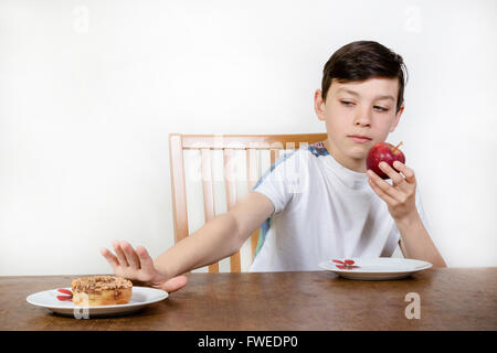 Junge, die Wahl auf einen Apfel statt einen Donut Essen Stockfoto