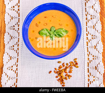 Rote Creme Linsensuppe mit gewürzte geröstete Kürbiskerne, Olivenöl und Basilikum Blätter garnieren Stockfoto