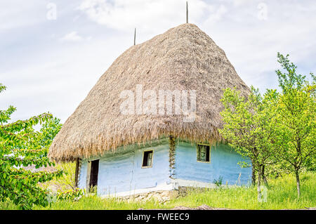 Leichte blaue Ton Altbau mit einem Strohdach, sichtbaren Holzbalken und Steinfundament. Stockfoto