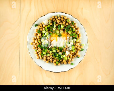 Kichererbsen mit Spiegelei und frischen Zwiebeln auf Platte Stockfoto