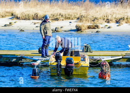 Kivik, Schweden - 1. April 2016: Zwei Männer immer bereit, eine gelbe Motorboot für Angeln herausnehmen. Eine Person Stand auf dem pi Stockfoto