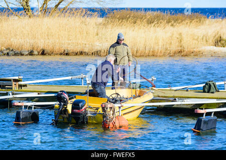 Kivik, Schweden - 1. April 2016: Zwei Männer immer bereit, eine gelbe Motorboot für Angeln herausnehmen. Eine Person Stand auf dem pi Stockfoto