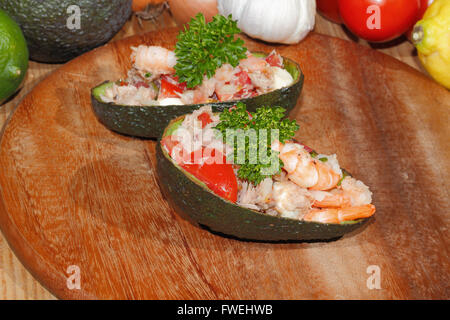 Teller mit Tomatensalat, Thunfisch und Garnelen gefüllte Avocados, garniert mit Petersilie, Zitrone, Zwiebel, Knoblauch, Tomaten und avocado Stockfoto