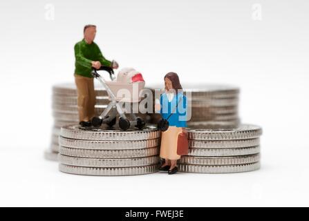 Eine Miniatur Figur Ehepaar mit einem Kinderwagen stehen auf farbigen Silbermünzen Stockfoto