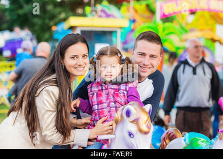 Vater, Mutter, Tochter genießen Kirmes Fahrt, Vergnügungspark Stockfoto