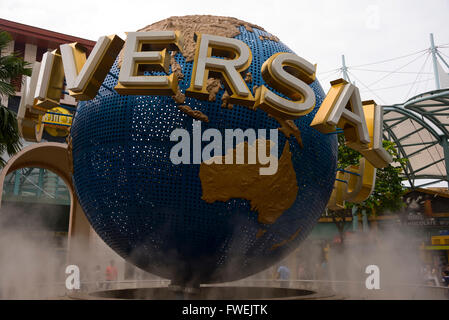 Besucher bewundern die wirbelnden Nebel rund um den drehenden Globus in den Universal Studios auf der Insel Sentosa in Singapur. Stockfoto