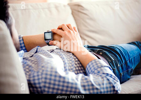 Mann auf Sofa zu Hause mit smart-Watch Stockfoto