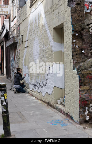 Eine junge Frau-Künstler Malerei ein abstraktes Bild an einer Wand in London, England, Vereinigtes Königreich. Stockfoto