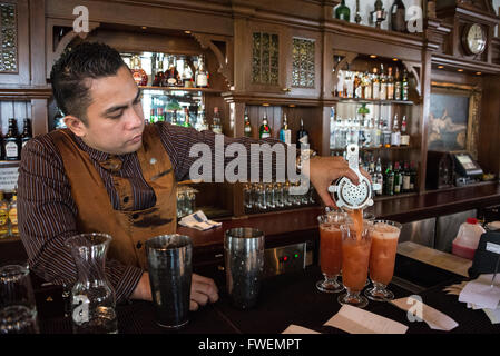 Ein Barkeeper, der den berühmten Cocktail-Drink „Singapore Sling“ in der Long Bar im Rafales Hotel in Singapur zubereitet. Stockfoto