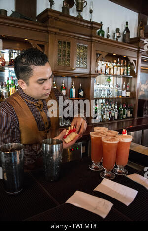 Ein Barkeeper, der den berühmten Cocktail-Drink „Singapore Sling“ in der Long Bar im Rafales Hotel in Singapur zubereitet. Stockfoto