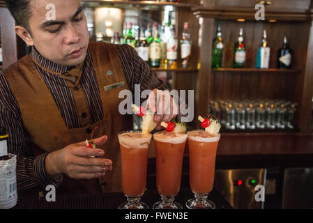 Ein Barkeeper, der den berühmten Cocktail-Drink „Singapore Sling“ in der Long Bar im Rafales Hotel in Singapur zubereitet. Stockfoto