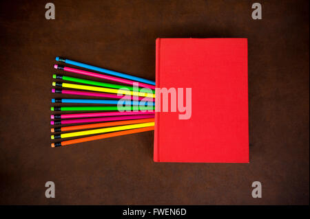 Hölzerne Desktop mit bunten Bleistift und Rotes Buch mit leeren Deckel Stockfoto