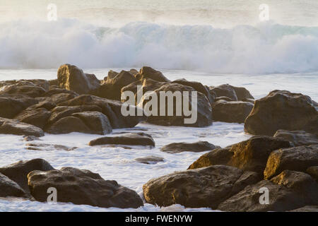 Weißer schaumiger Wasser herein gefährlich über einige Felsen auf der Nordküste von Oahu während ein gewaltiger Sturm im Ozean. Stockfoto