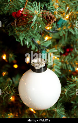 Trauringe hängen eine Christbaumkugel bei einer Winterhochzeit. Stockfoto