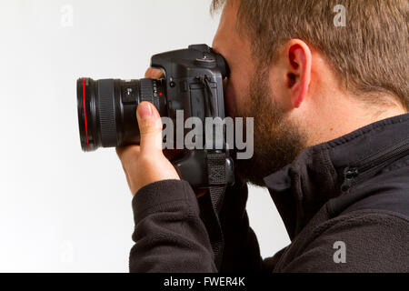 Ein Fotograf hält die Kamera, wie er Fotos schießt. Stockfoto