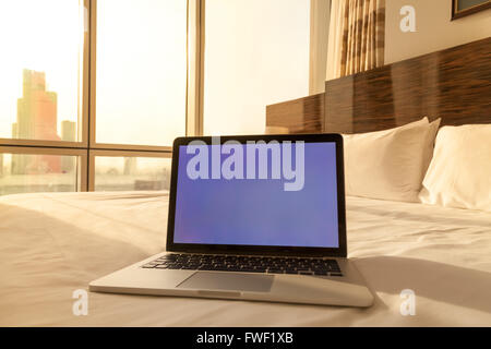 Laptop-Computer auf weißer Bettwäsche in gemütliche Hotelzimmer mit Kopie Raum leerer Bildschirm Stockfoto
