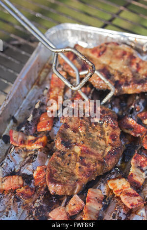 Gegrilltes Steak mit Speck auf ein Aluminium-Tablett, das tropfende Fett ins Feuer verhindert. Stockfoto