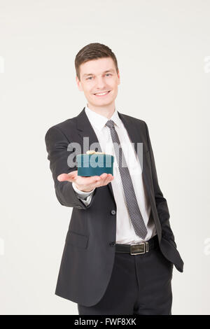 Hübscher junger Mann mit Geschenk-Box auf dem grauen Hintergrund. Stockfoto