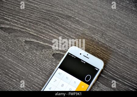 Ein Apple iPhone 6 s auf der Oberfläche des Holzes mit der Rechner-Anwendung auf dem Bildschirm angezeigt Stockfoto