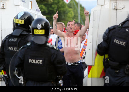 Bewaffnete Polizisten beobachten Loyalisten während der Schwierigkeiten im Norden Belfast nach einem anhaltenden Angriff auf Polizei im Bereich Woodvale Stockfoto