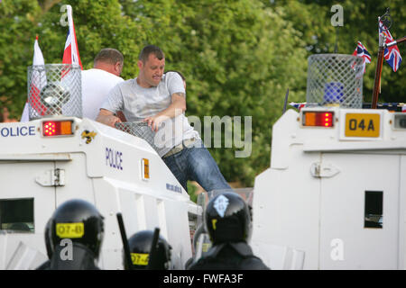 Bewaffnete Polizisten beobachten Loyalisten während der Schwierigkeiten im Norden Belfast nach einem anhaltenden Angriff auf Polizei im Bereich Woodvale Stockfoto