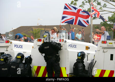 Bewaffnete Polizisten beobachten Loyalisten während der Schwierigkeiten im Norden Belfast nach einem anhaltenden Angriff auf Polizei im Bereich Woodvale Stockfoto