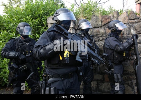 Bewaffnete Polizisten beobachten Loyalisten während der Schwierigkeiten im Norden Belfast nach einem anhaltenden Angriff auf Polizei im Bereich Woodvale Stockfoto