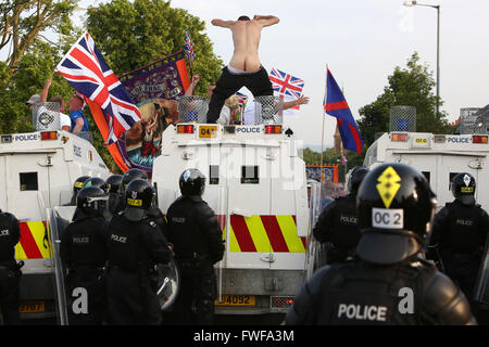 Bewaffnete Polizisten beobachten Loyalisten während der Schwierigkeiten im Norden Belfast nach einem anhaltenden Angriff auf Polizei im Bereich Woodvale Stockfoto