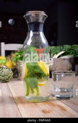 Minze und Zitrone gewürzt Wasser vor frisches Bio-Obst und Gemüse auf einer Tischplatte Stockfoto