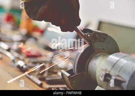 Vintage Foto mit Mechaniker Polieren eine Schraube am industriellen Poliermaschine in einer Garage. Sparks entstammen Schleifscheibe. Stockfoto