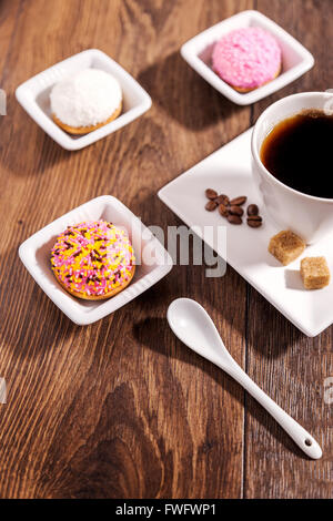 Tasse Kaffee und Marshmallow Kekse mit Zuckerguss farbige Granulate auf weißer Keramik Untertasse Stockfoto