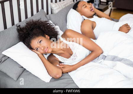 Nachdenkliche Frau liegt in ihrem Bett Stockfoto