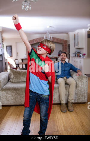 Sohn, die vorgibt, ein Superheld während Vater auf sofa Stockfoto