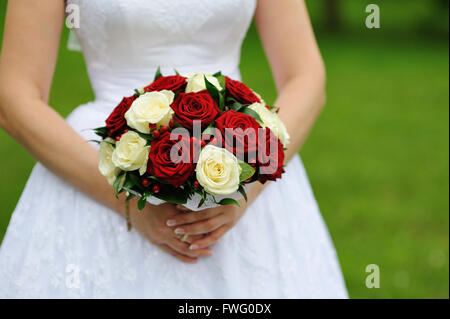 rote und weiße Hochzeit Bouquet Rosen in den Händen der Braut Stockfoto